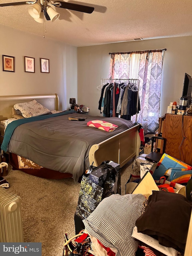 carpeted bedroom featuring ceiling fan and a textured ceiling