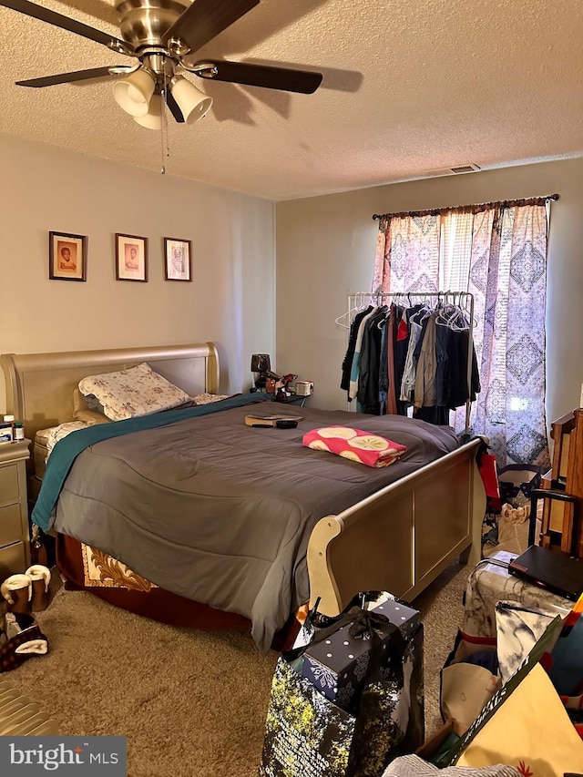 bedroom with carpet, a textured ceiling, and ceiling fan