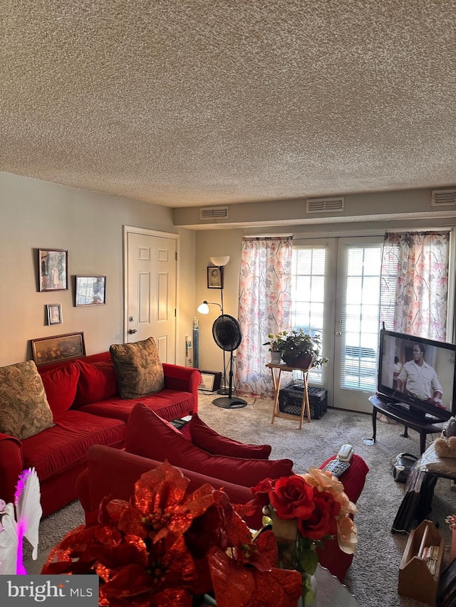 carpeted living room with a textured ceiling and french doors