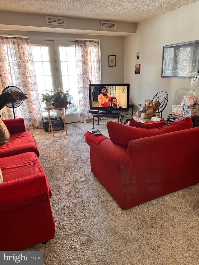 carpeted living room with a textured ceiling and french doors