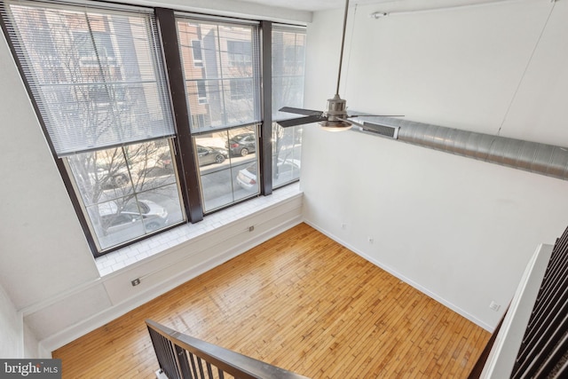 interior space featuring wood-type flooring, a ceiling fan, and baseboards