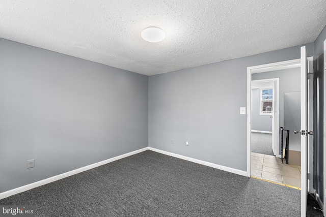 carpeted empty room featuring a textured ceiling