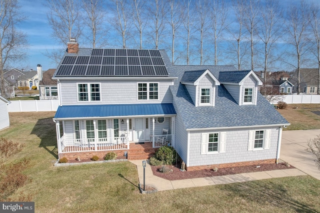 view of front of home featuring a front yard, solar panels, and a porch