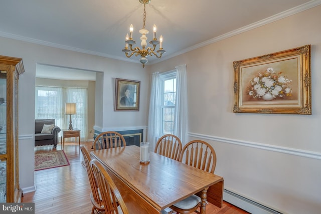 dining space featuring ornamental molding, a baseboard heating unit, a notable chandelier, and light wood-type flooring