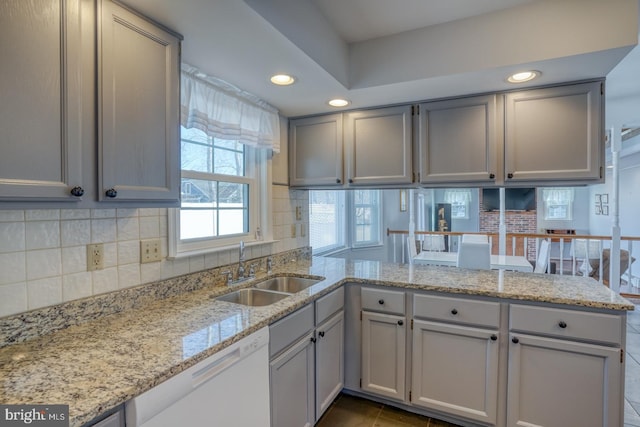 kitchen featuring sink, decorative backsplash, white dishwasher, and kitchen peninsula