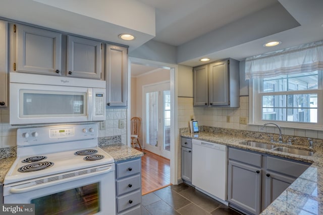 kitchen featuring sink, gray cabinets, white appliances, light stone countertops, and backsplash