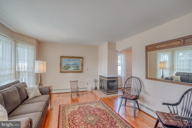 living room featuring light wood-type flooring, a fireplace, and baseboard heating