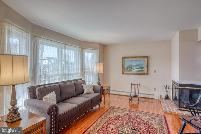 living room featuring a multi sided fireplace, a baseboard heating unit, and hardwood / wood-style floors