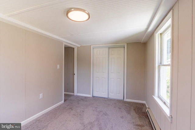 unfurnished bedroom with light carpet, a baseboard heating unit, and a closet