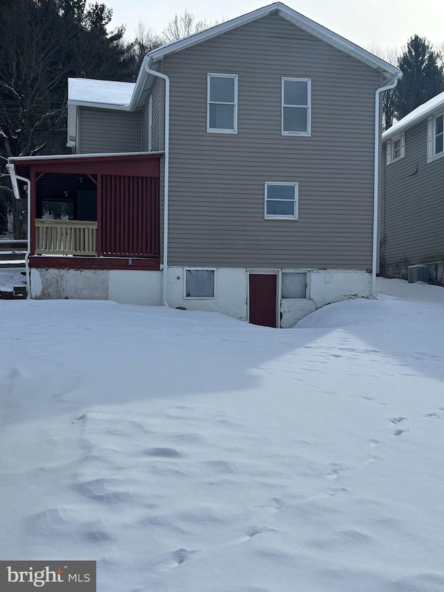 snow covered house featuring covered porch