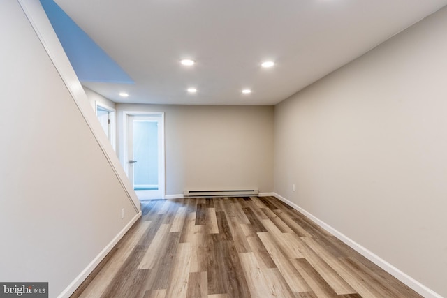 basement with a baseboard heating unit and light wood-type flooring