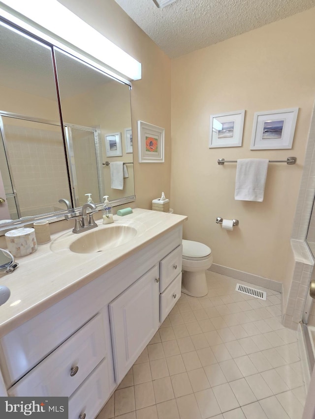 bathroom featuring tile patterned flooring, vanity, toilet, a shower with door, and a textured ceiling