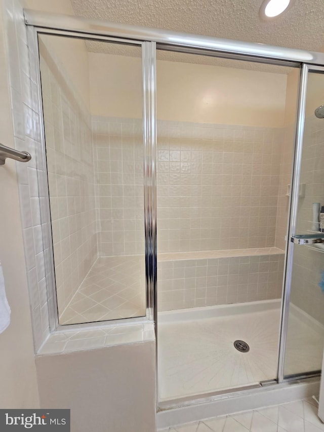 bathroom featuring a shower with shower door and a textured ceiling