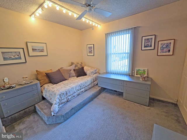 bedroom featuring ceiling fan, dark carpet, track lighting, and a textured ceiling