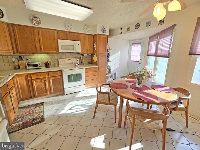 kitchen with pendant lighting, white appliances, ceiling fan, backsplash, and a textured ceiling