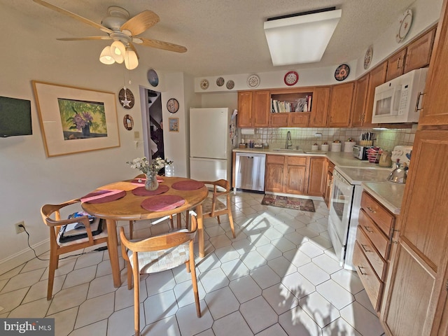 kitchen featuring sink, decorative backsplash, light tile patterned floors, ceiling fan, and white appliances