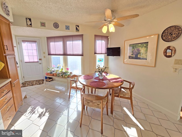 dining space featuring light tile patterned flooring, ceiling fan, and a textured ceiling