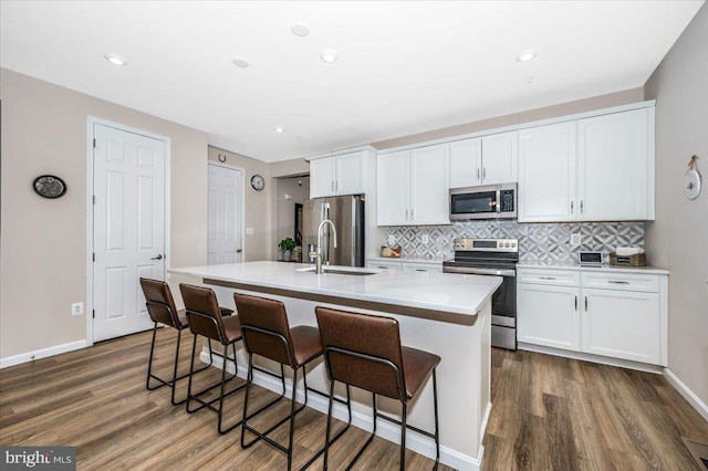 kitchen with tasteful backsplash, white cabinetry, appliances with stainless steel finishes, and a center island with sink