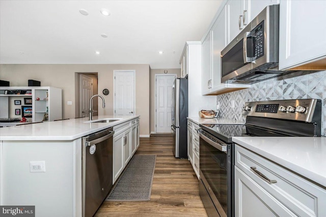 kitchen with appliances with stainless steel finishes, sink, a kitchen island with sink, and white cabinets