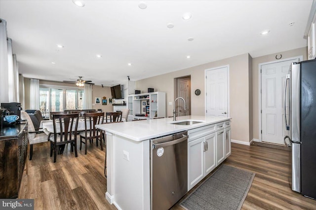 kitchen with white cabinetry, stainless steel appliances, sink, and a center island with sink