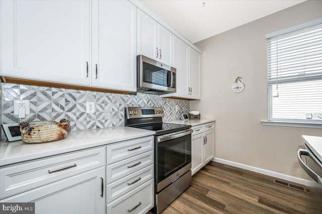 kitchen with tasteful backsplash, white cabinetry, appliances with stainless steel finishes, and dark hardwood / wood-style floors