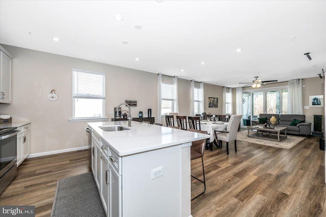 kitchen featuring sink, white cabinetry, electric range, hardwood / wood-style flooring, and a kitchen island with sink