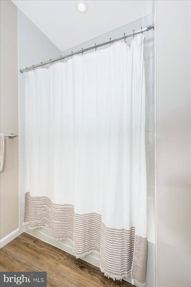 bathroom with shower / tub combo with curtain and hardwood / wood-style flooring