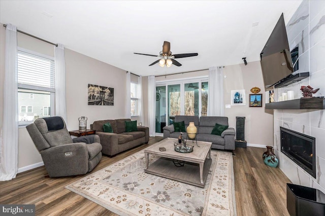 living room with ceiling fan, plenty of natural light, dark wood-type flooring, and a fireplace