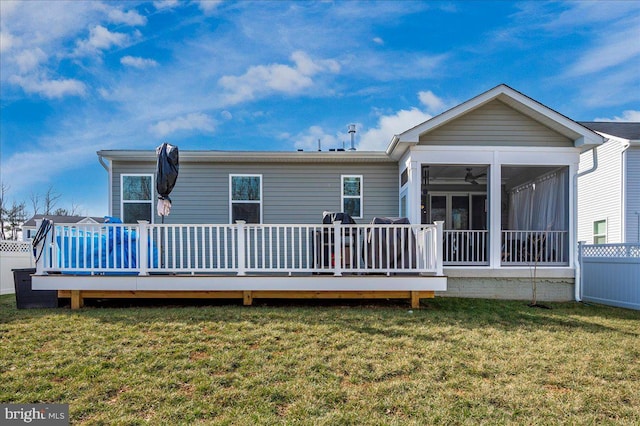 back of house featuring a sunroom, a deck, and a lawn