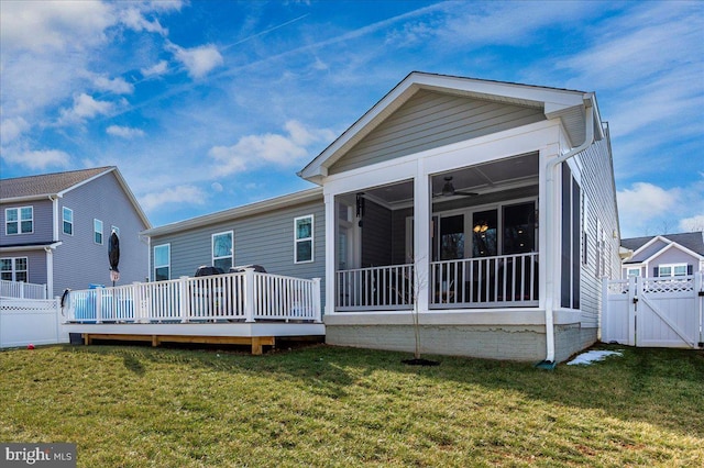 rear view of property with a yard, a sunroom, and a deck