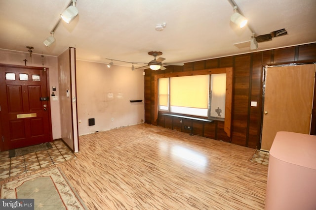 foyer entrance featuring ceiling fan and wood walls