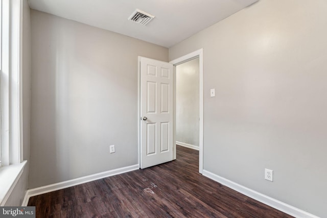 unfurnished room with dark wood-type flooring