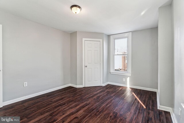 unfurnished room with dark wood-type flooring