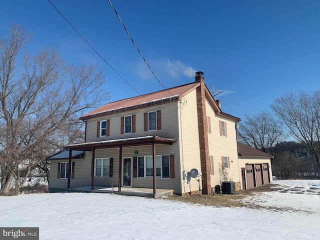 view of front of house featuring a garage, a porch, and central AC unit