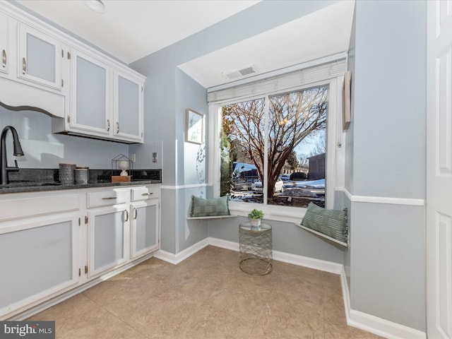 kitchen featuring white cabinetry, sink, dark stone countertops, and light tile patterned flooring