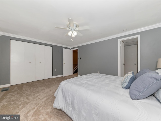 carpeted bedroom featuring crown molding, a closet, and ceiling fan