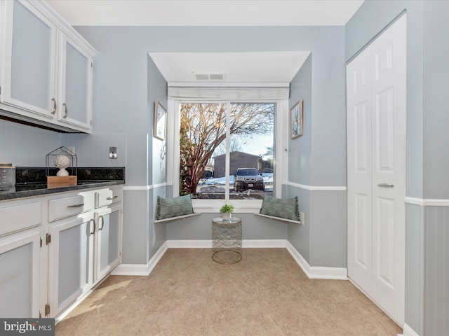 kitchen featuring light tile patterned flooring, dark stone countertops, and white cabinets