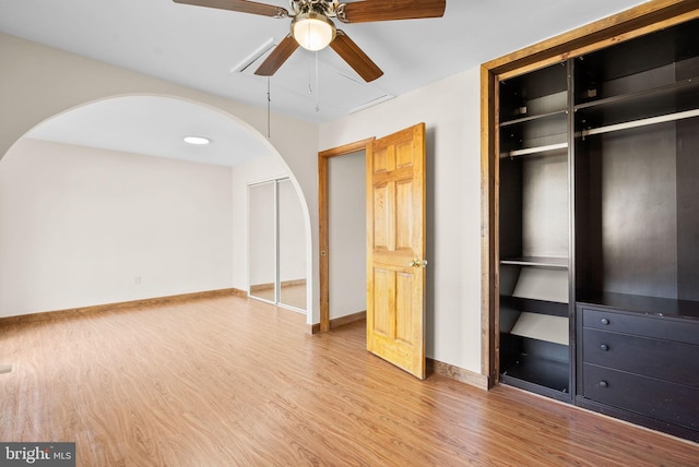 unfurnished bedroom featuring ceiling fan, multiple closets, and light wood-type flooring