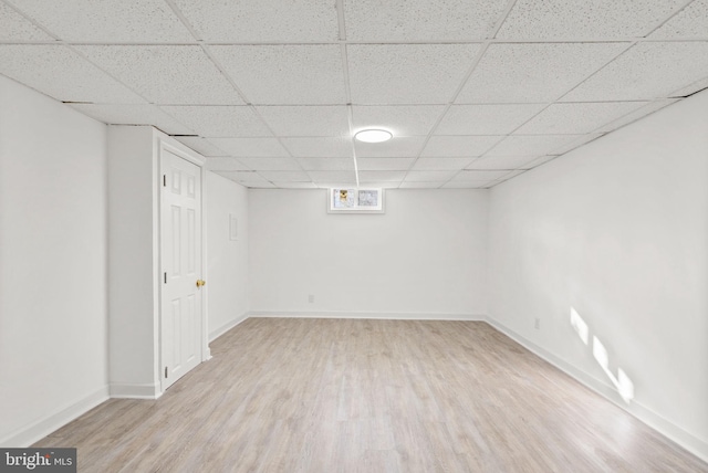 basement featuring light hardwood / wood-style flooring and a paneled ceiling