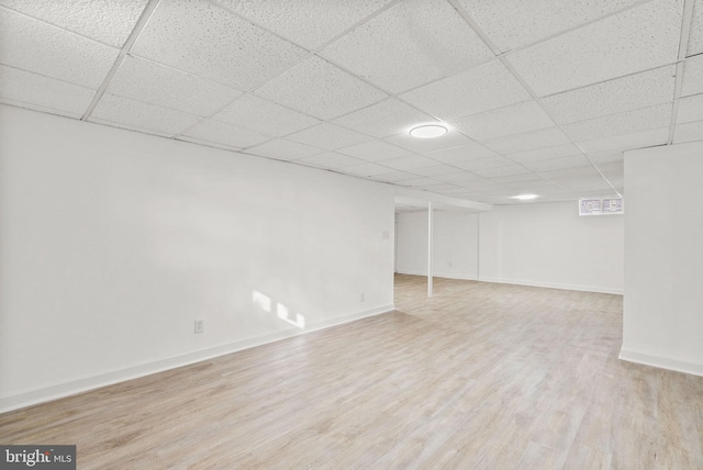 basement with a paneled ceiling and light hardwood / wood-style floors