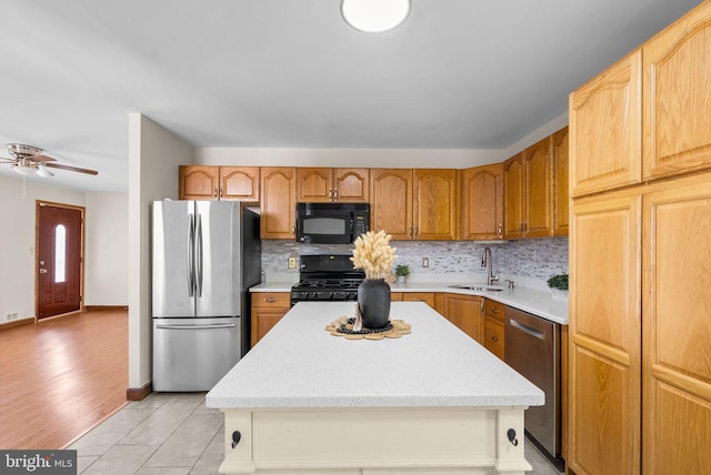 kitchen with light tile patterned flooring, sink, black appliances, a center island, and backsplash