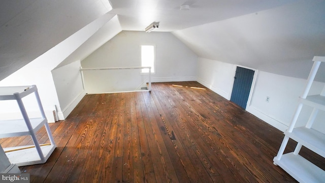 additional living space featuring dark wood-type flooring and vaulted ceiling