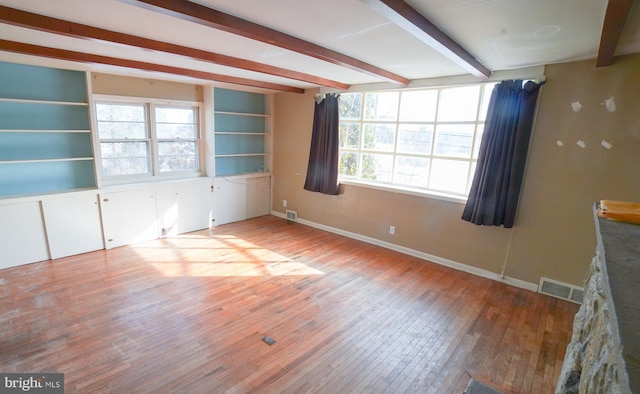 spare room featuring built in features, beam ceiling, and light hardwood / wood-style flooring