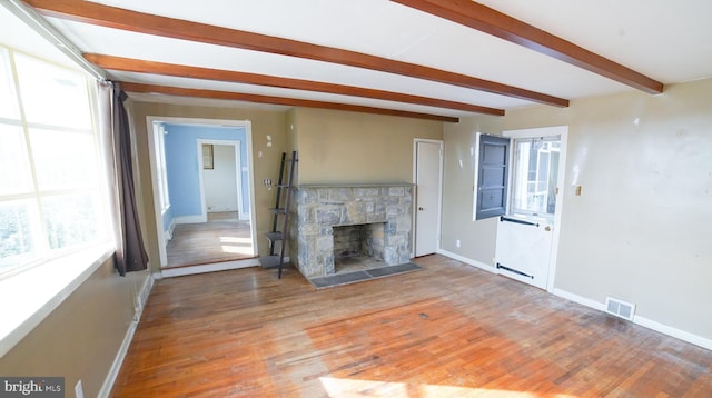 unfurnished living room featuring beam ceiling, hardwood / wood-style flooring, and a fireplace