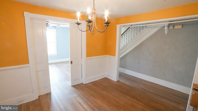 unfurnished dining area featuring hardwood / wood-style flooring and an inviting chandelier