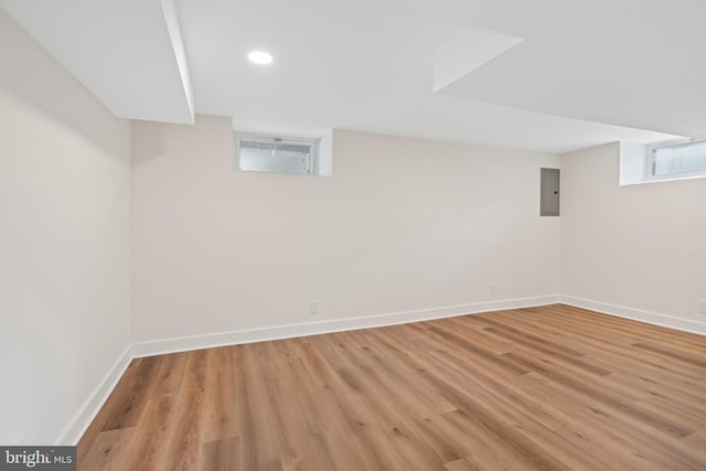 basement featuring electric panel and light hardwood / wood-style floors