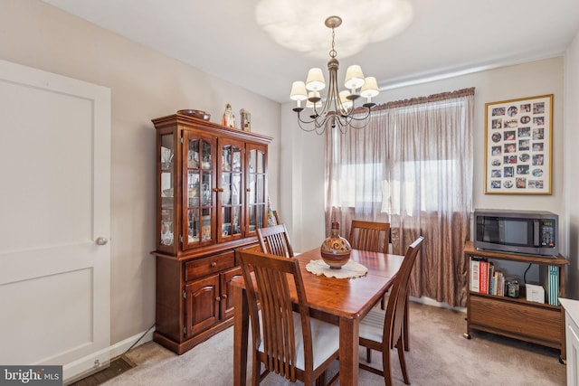 dining space with an inviting chandelier and light colored carpet