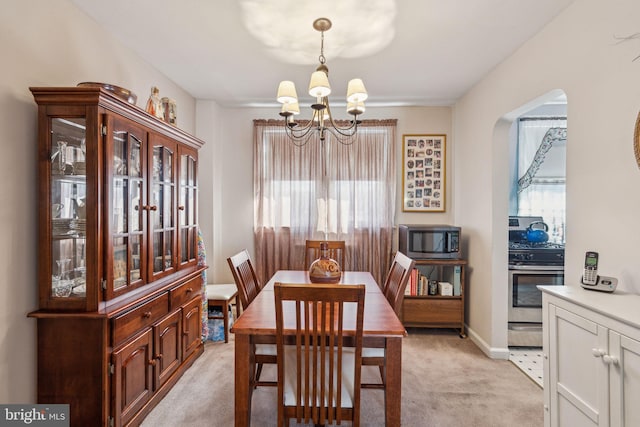 dining area with a healthy amount of sunlight, light colored carpet, and a notable chandelier