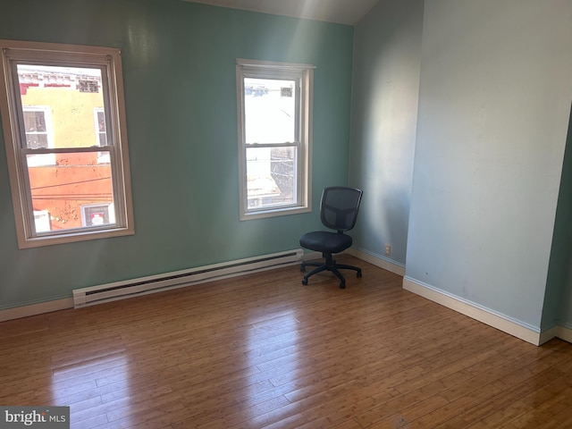 empty room with a baseboard heating unit and hardwood / wood-style floors