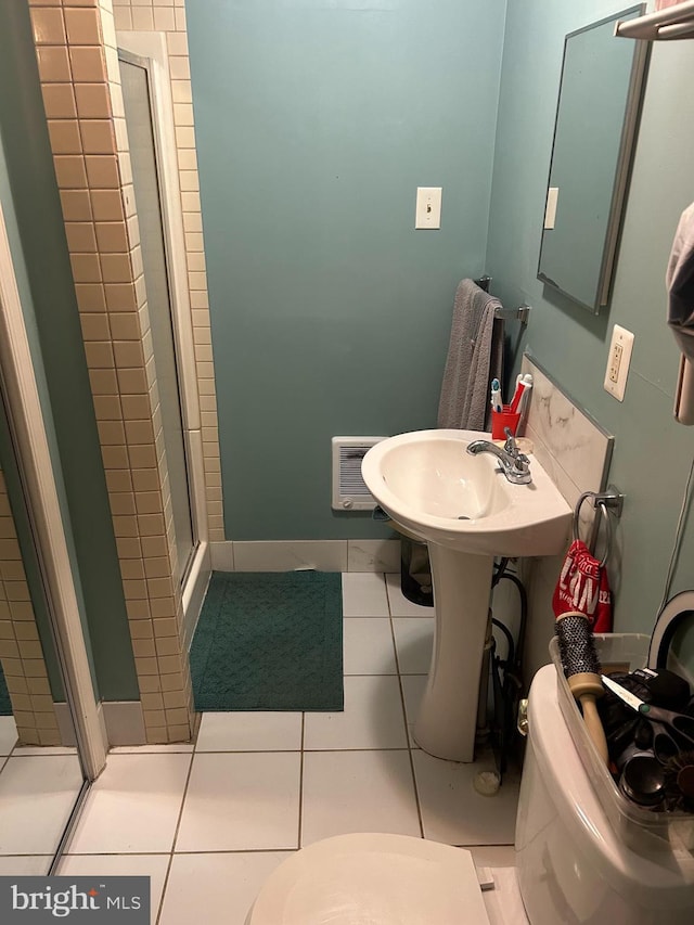 bathroom with toilet, a shower with shower door, and tile patterned flooring